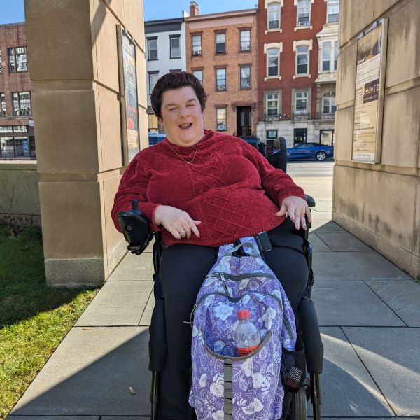 A woman in a wheelchair wearing a red sweater