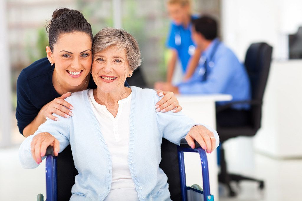 Caring younger woman with older woman in wheelchair