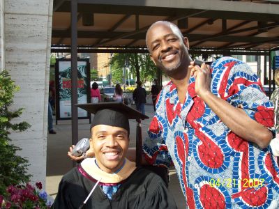 2 black men smiling. The man in the wheelchair is graduating.