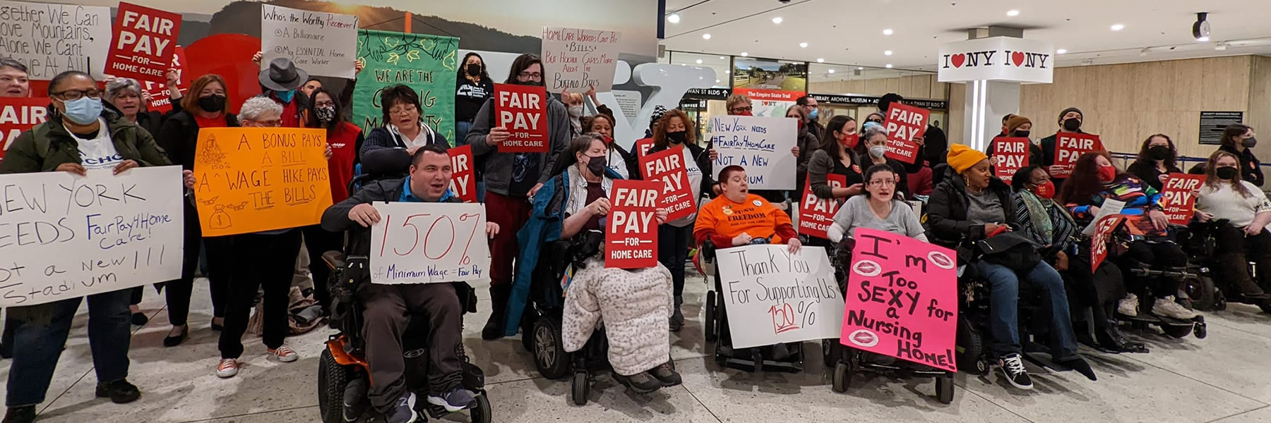 Large group of people holding signs for increase in minimum wage and home care advocacy