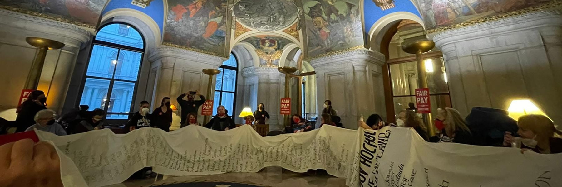 Group seated in a circle in the war room of the Capitol prior to arrest. The long scroll is a list of NYers who submitted names who can't find home care.